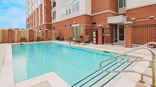 a swimming pool with chairs and a building at Hyatt Place Austin/Round Rock in Round Rock
