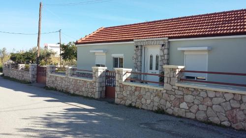 a house with a stone wall and a fence at Anastasia's garden house in Ialyssos