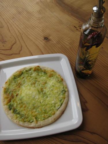 a pizza sitting on a white plate on a table at Kumano Backpackers in Tanabe