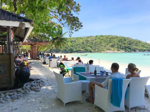 a group of people sitting at tables on the beach at Racha Island Resort (Rayaburi) in Ko Racha Yai 
