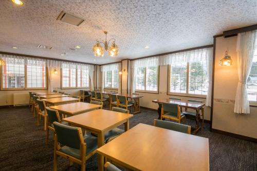 a dining room with tables and chairs and windows at Rosenheim Hakuba in Hakuba
