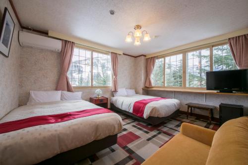 a hotel room with two beds and a tv at Rosenheim Hakuba in Hakuba