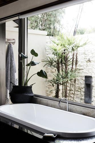 a bathroom with a white tub in front of a window at The Villas of Byron in Byron Bay