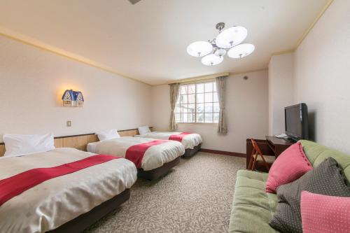 a hotel room with two beds and a tv at Rosenheim Hakuba in Hakuba