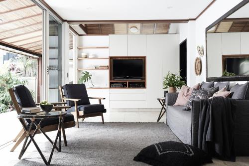 a living room with a couch and chairs and a tv at The Villas of Byron in Byron Bay