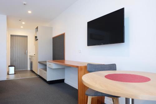 a room with a desk and a table with a television on the wall at Stopforths Motel in Hokitika