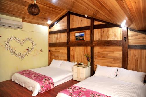 two beds in a room with wooden walls at Fengnan Tianzhuang Homestay in Fuli