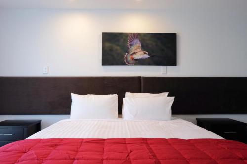 a bedroom with a large bed with a red comforter at Stopforths Motel in Hokitika