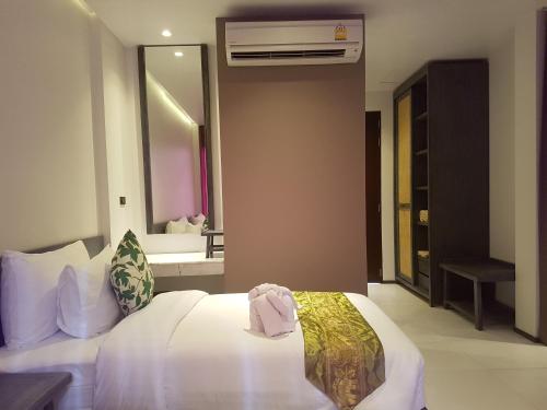 a bedroom with a white bed and a mirror at Maehaad Bay Resort - SHA Plus in Mae Haad