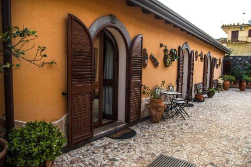 a building with wooden doors and a patio with plants at B&B Villa Liliya in Fiumefreddo di Sicilia