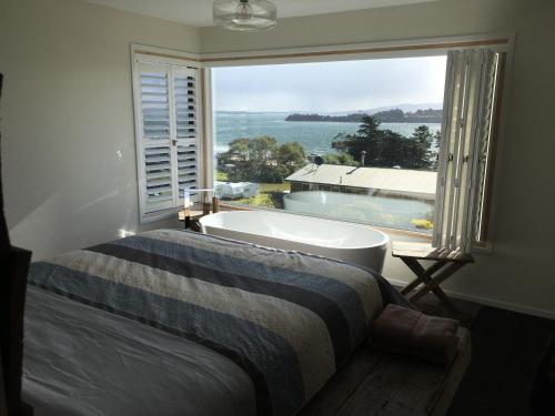 a bedroom with a bath tub and a large window at Couples Getaway on Bruny Island in Alonnah