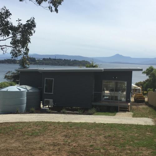 a black house sitting next to a body of water at Couples Getaway on Bruny Island in Alonnah