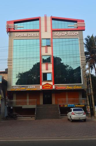 a building with a car parked in front of it at SUPREME LODGe in Dharmastala