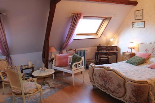 a bedroom with a bed and chairs and a window at La ferme de la vallée in Auchy-au-Bois