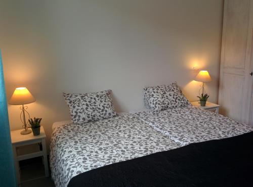a bedroom with a black and white bed with two lamps at La Cigale - Pte des Gorges - Piscine privée chauffée in Vallon-Pont-dʼArc