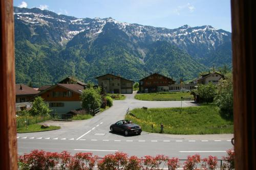 a car driving down a road with mountains in the background at Lakeside Apartment in Ringgenberg