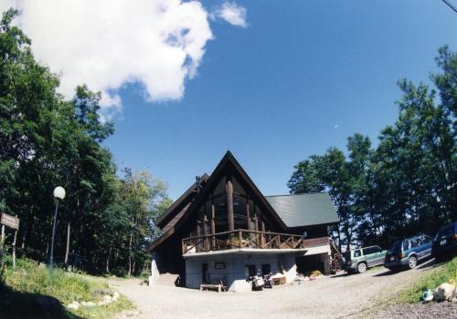 a large wooden house with a gambrel roof at Pension Gooseberry in Furano