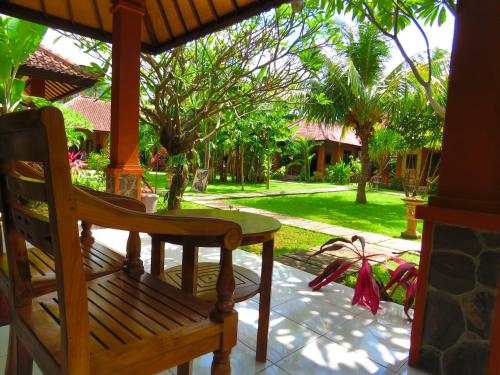 a wooden table and a chair on a porch at Suka Sari Cottages in Pemuteran