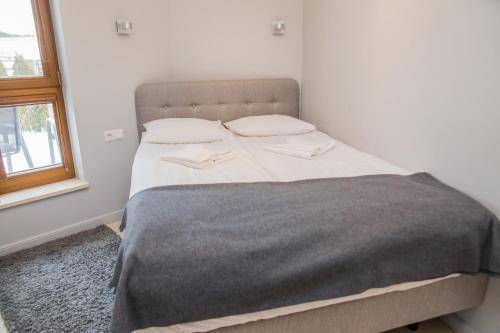 sypialnia z łóżkiem z szarym kocem i oknem w obiekcie Family Homes - Apartamenty Gwiazda Morza we Władysławowie