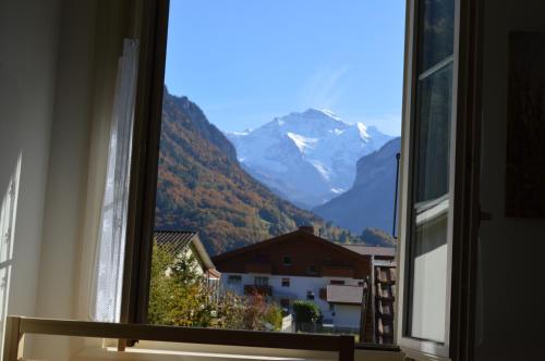 a window with a view of a snowy mountain at Jungfrau Family Holiday Home in Matten