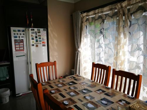 a dining room table with chairs and a refrigerator at Monique's Rose Room Prvt BthRm AC TV in Auckland