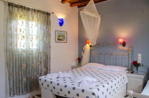 a bedroom with a white bed and a window at Lakki Village in Aegiali