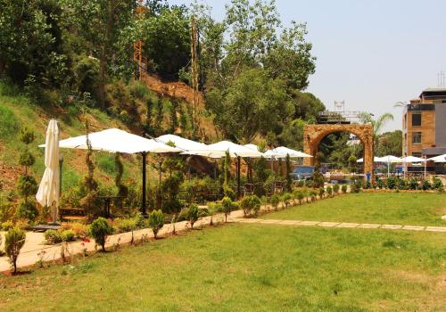 a garden with umbrellas and plants in a park at Le Caravelle Beirut in Beirut