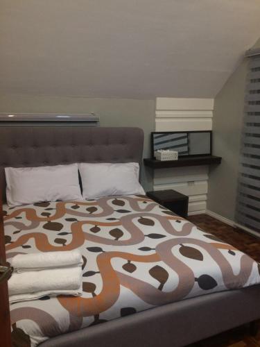 a bedroom with a bed with a brown and white blanket at Hillary Timog Park Homes in Angeles