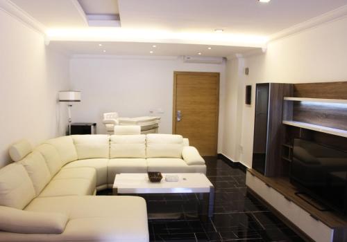 a living room with white couches and a television at Le Caravelle Beirut in Beirut