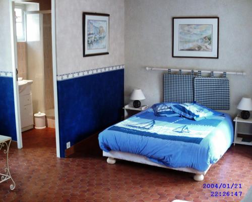 een slaapkamer met een bed met een blauw dekbed bij L'eau vive in Amblie