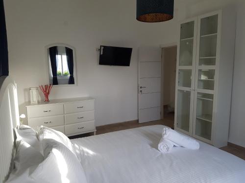 a bedroom with a white bed and a dresser at אבני החושן- Avnei Hoshen in Nahariyya