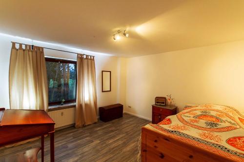 a bedroom with a bed and a desk and a window at Villa im Reiterdorf in Beverstedt