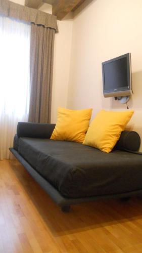 a couch with yellow pillows and a tv on the wall at Ristolocanda Grani Di Pepe in Flaibano