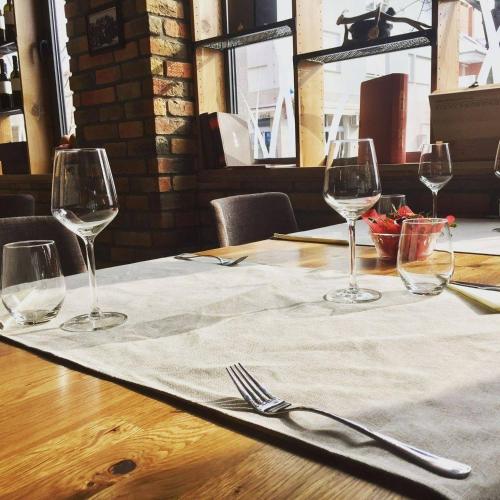 a table with four wine glasses and a napkin at Rooms The King's Pub in Kutina