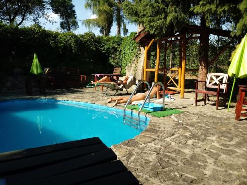 two people laying on towels next to a swimming pool at Farma Zdrowia in Znamirowice