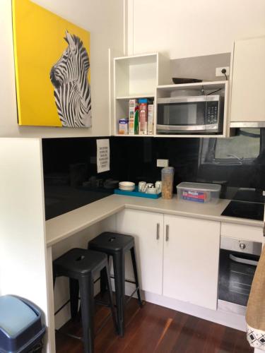 a kitchen with a counter with stools and a microwave at Gin Gin Budget Accommodation in Gin Gin