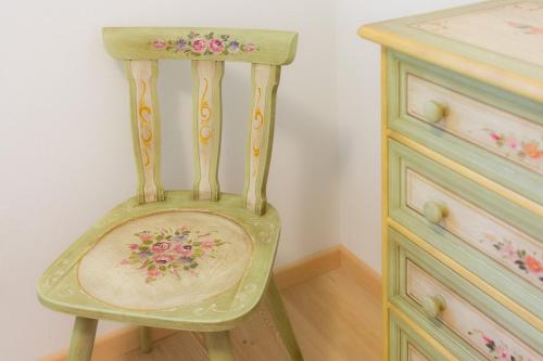 a green chair with flowers on it next to a dresser at Villa Edelweiss in Alleghe