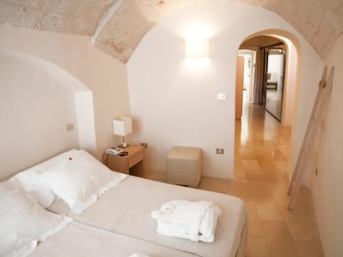 a bedroom with a white bed and a hallway at La Sommità Relais & Chateaux in Ostuni