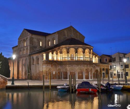 a large building with boats in the water at night at DUOMO Murano Apartment with Canal view in Murano