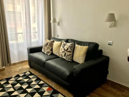 a black leather couch with pillows in a living room at Résidence du Forum des Halles in Paris