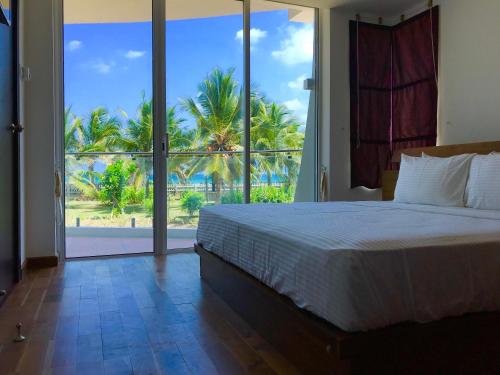 a bedroom with a bed and a view of the ocean at Nilaveli Ocean Condos in Trincomalee