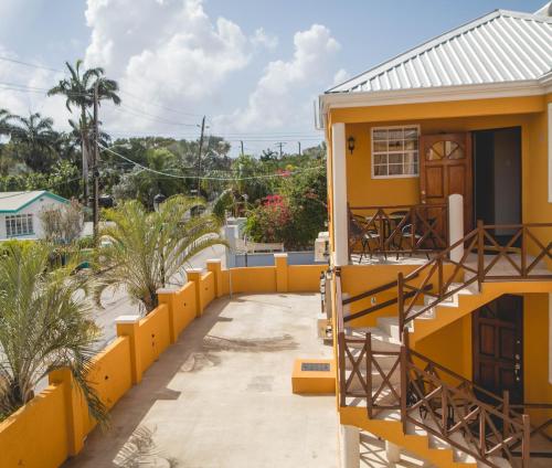 a house with a yellow fence next to a walkway at Frontline Apartments in Christ Church