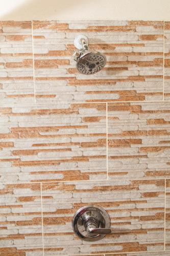 a brick wall with a shower in a bathroom at Frontline Apartments in Christ Church