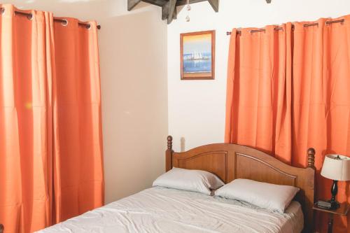a bedroom with orange curtains and a bed at Frontline Apartments in Christ Church