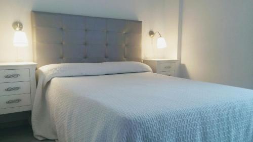 1 dormitorio con 1 cama blanca, 2 mesitas de noche y 2 luces en Residencial Torre Bermeja, en Estepona