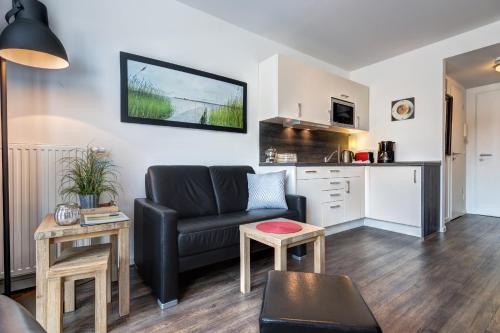 ein Wohnzimmer mit einem Sofa und einer Küche in der Unterkunft Residenz am Balmer See - BS 56 mit Wellnessbereich in Balm