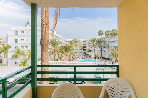d'un balcon avec vue sur la piscine et les palmiers. dans l'établissement Apartamento Chocolate, à Playa del Ingles