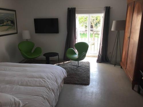 a bedroom with a bed and green chairs and a window at Les terres in Chaponost