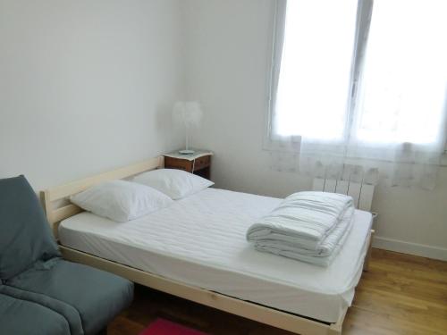 Una cama con sábanas blancas y un sofá en una habitación en à 50 mètres de la plage, en Île-Tudy