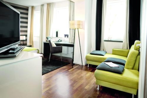 a living room with a yellow couch and a tv at City Hotel Bosse in Bad Oeynhausen